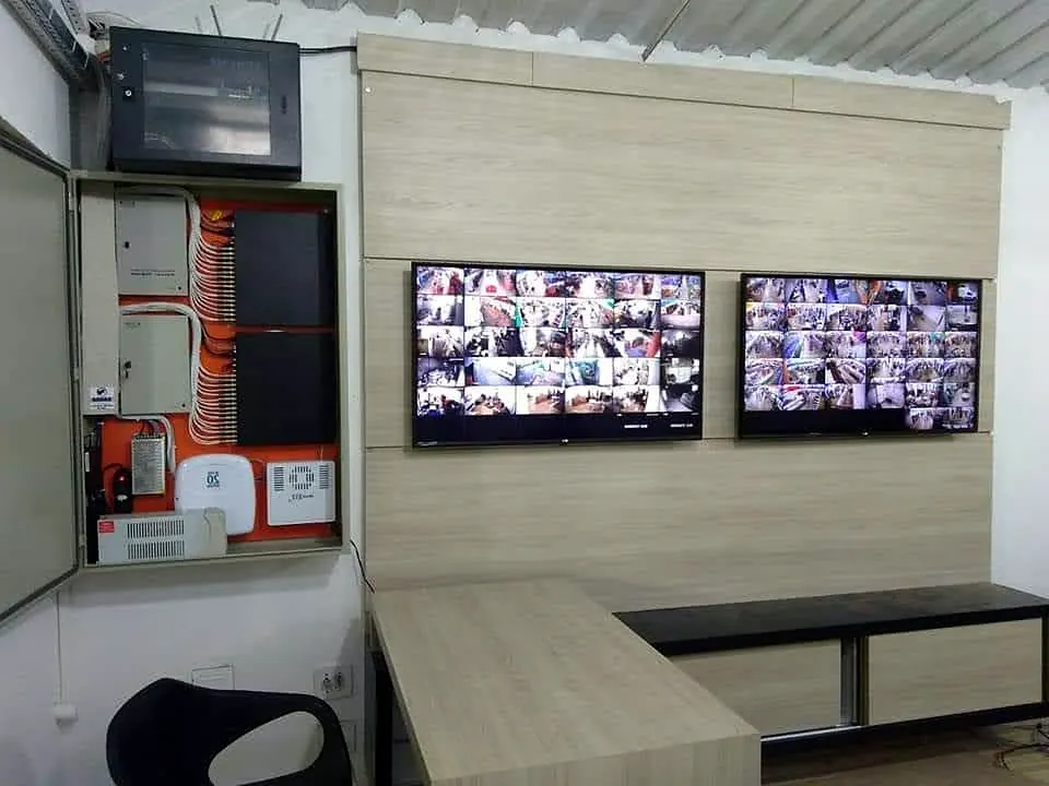 Sala de monitoramento com quadro elétrico e telas de CFTV