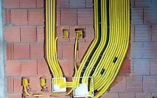 Quanto custa trocar a fiação de um apartamento em SP (2026) — Fiação nova passando por eletrodutos amarelos em parede de obra, antes do reboco