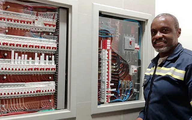 Elétrica comercial na Zona Norte de SP — Ronaldo Américo, de uniforme, ao lado de quadros elétricos de distribuição