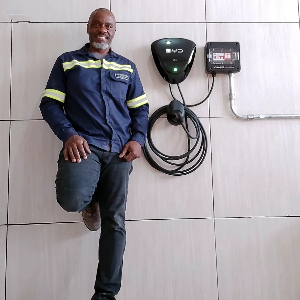 Ronaldo Américo ao lado de carregador de carro elétrico instalado na parede